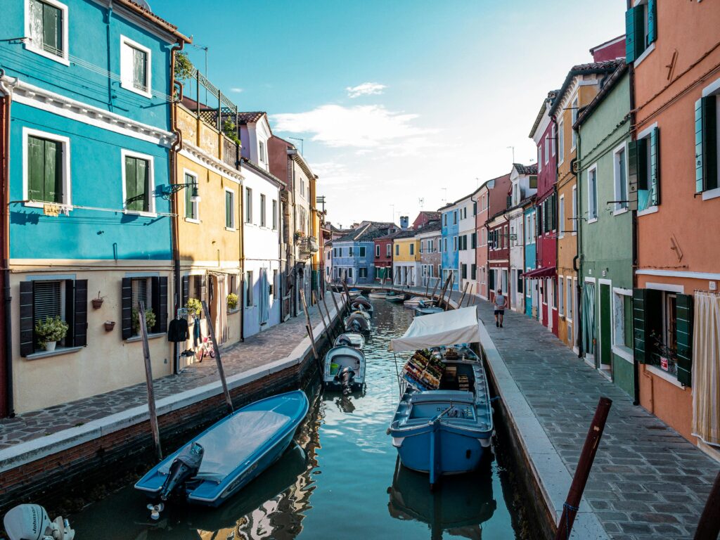 Vibrant houses and boats along a narrow canal in Venice, Italy, showcasing a picturesque setting.